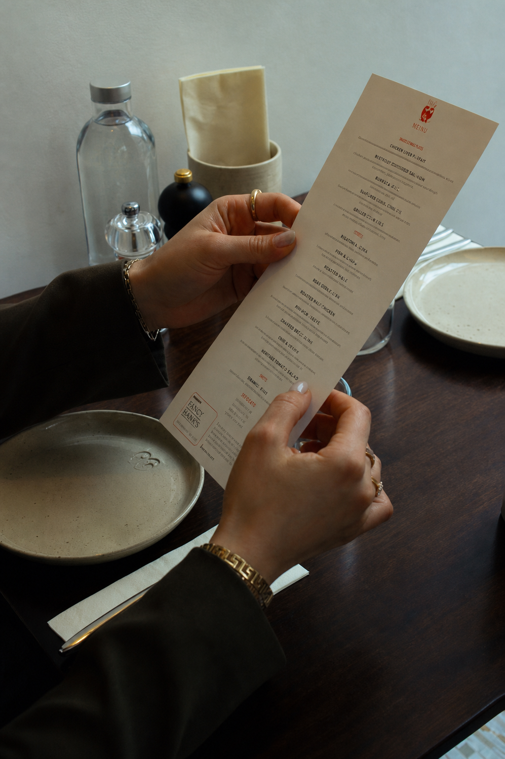Hands holding a printed menu at a restaurant table.